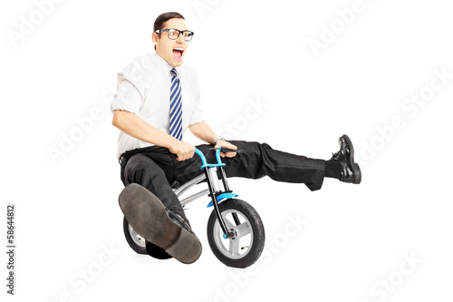 Nerdy young male with tie riding a small bicycle