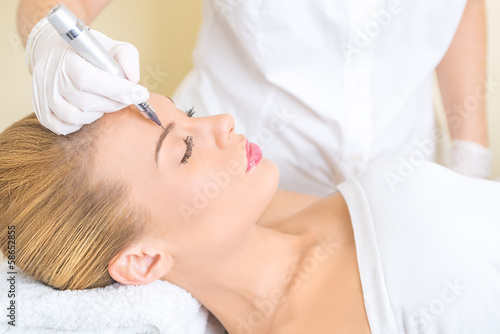 Cosmetologist applying permanent make up on eyebrows