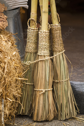 Close view of some straw brooms.