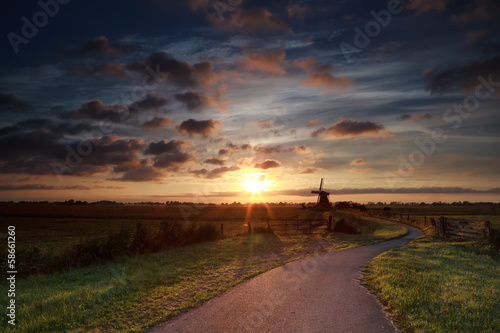 summer sunrise over Dutch windmill on farmland