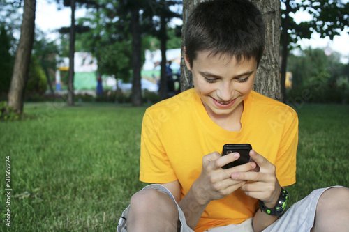 young man holding a smartphone and text message park photo