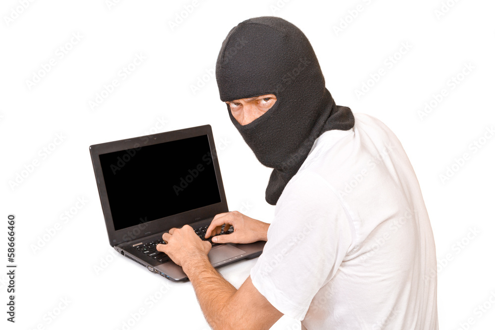 Man in black mask looking at camera and typing something Man in black mask looking at camera and typing something