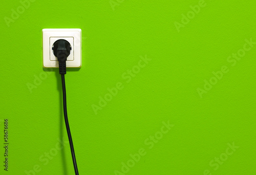 White power point with electric cable on green wall