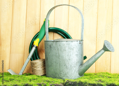 Gardening tools on grass on wooden background