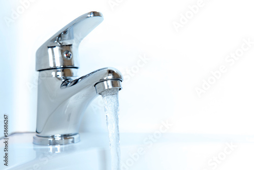 Close-up of human hands being washed under faucet in bathroom 