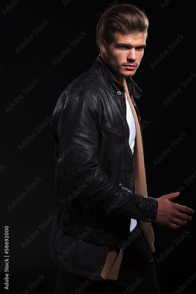 side view of a young man in leather jacket is walking