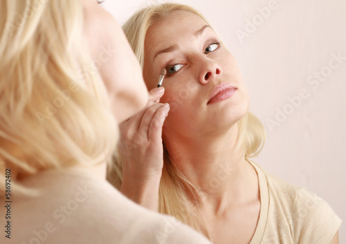 Woman caring of her skin on the face standing near mirror