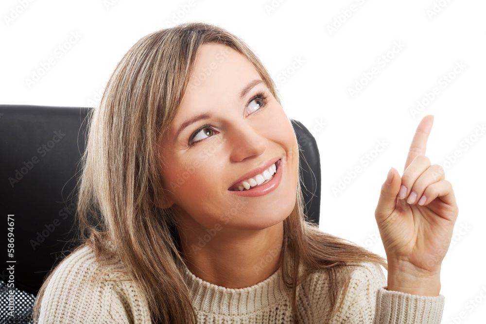 Young woman sitting on a chair and pointing up. Young woman sitting on a chair and pointing up.