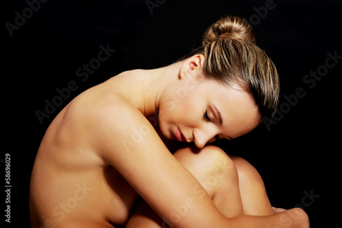 Nude woman sitting. Side view.