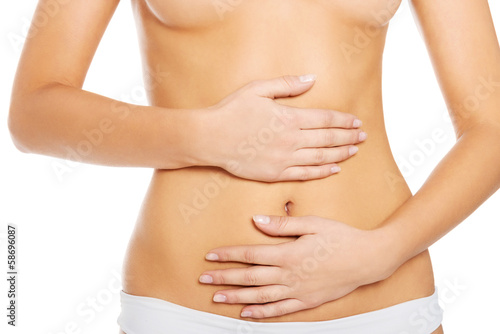 Slim and fit woman holds her hands on belly.
