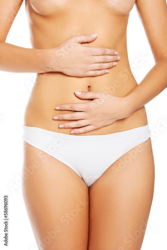 Slim and fit woman holds her hands on belly.