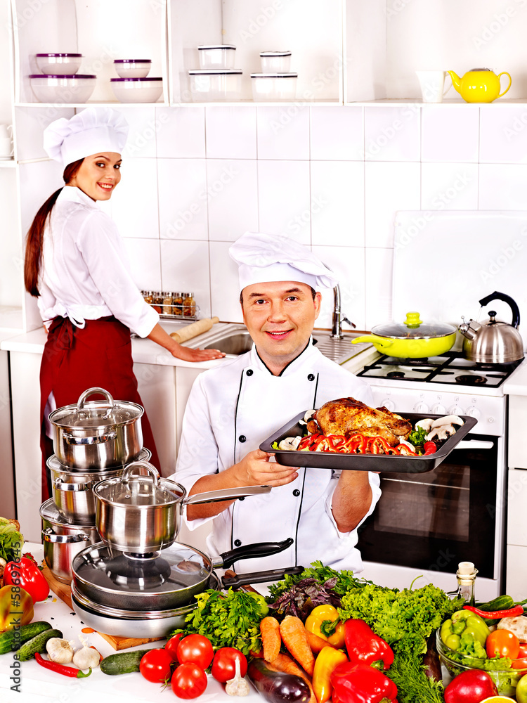 Man and woman in chef hat cooking chicken Man and woman in chef hat cooking chicken