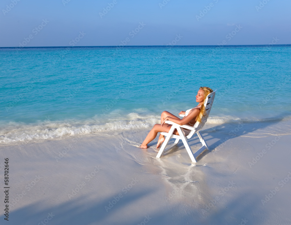 Young pretty woman tans in beach chair