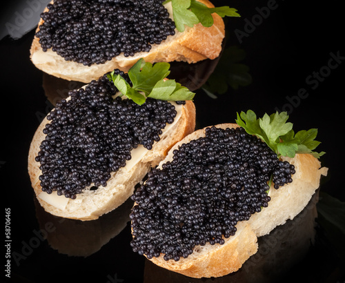 Small sandwiches with black caviar on dark plate