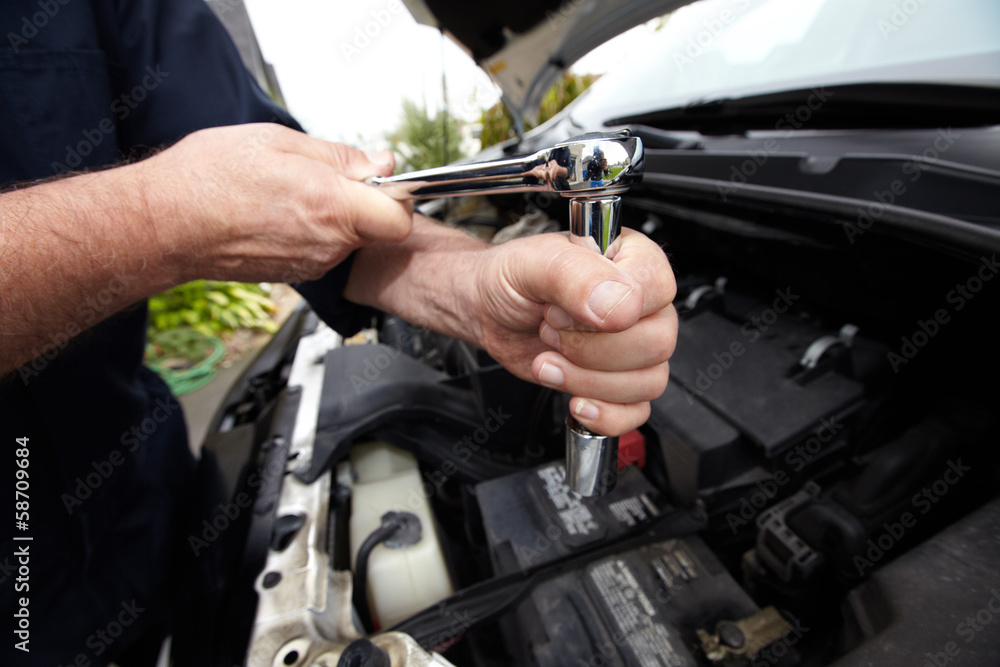 Hands of auto mechanic with wrench.