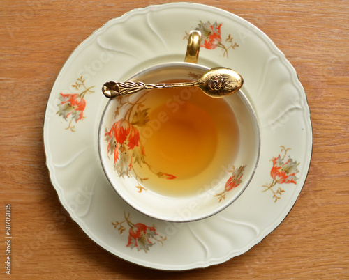 Cup of tea and teaspoon on wooden photo