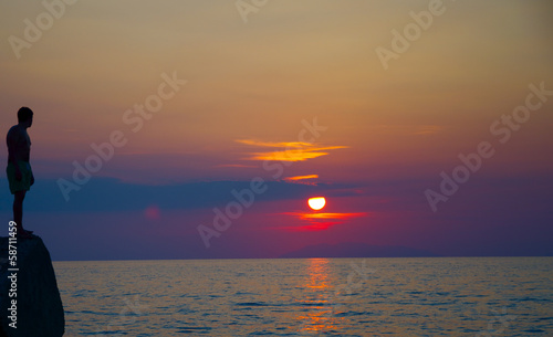 Silhouette of young man taking a dip at sea sunset