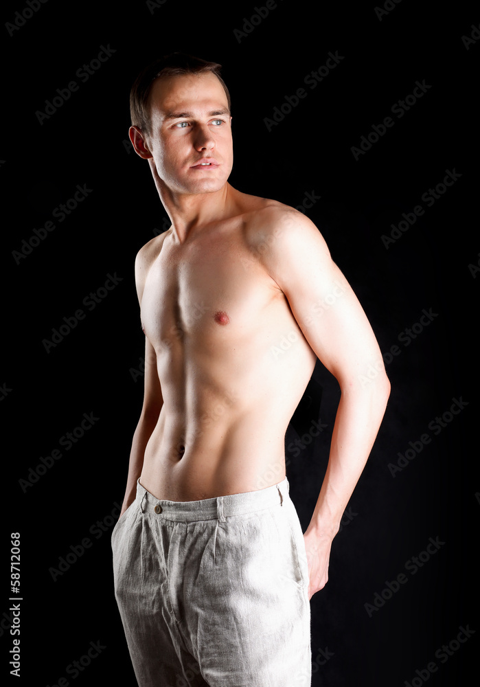 Fototapeta premium Portrait of a naked muscular man, isolated on black background