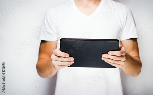 Man in white t-shirt using tablet pc, white wall on background