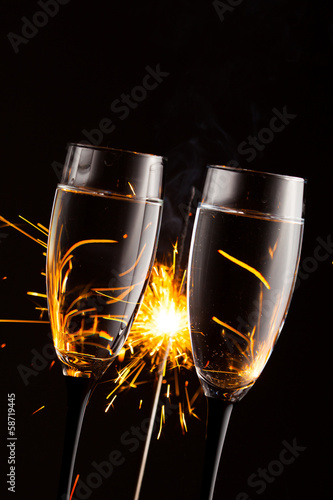 champagne glasses against christmas sparkler background