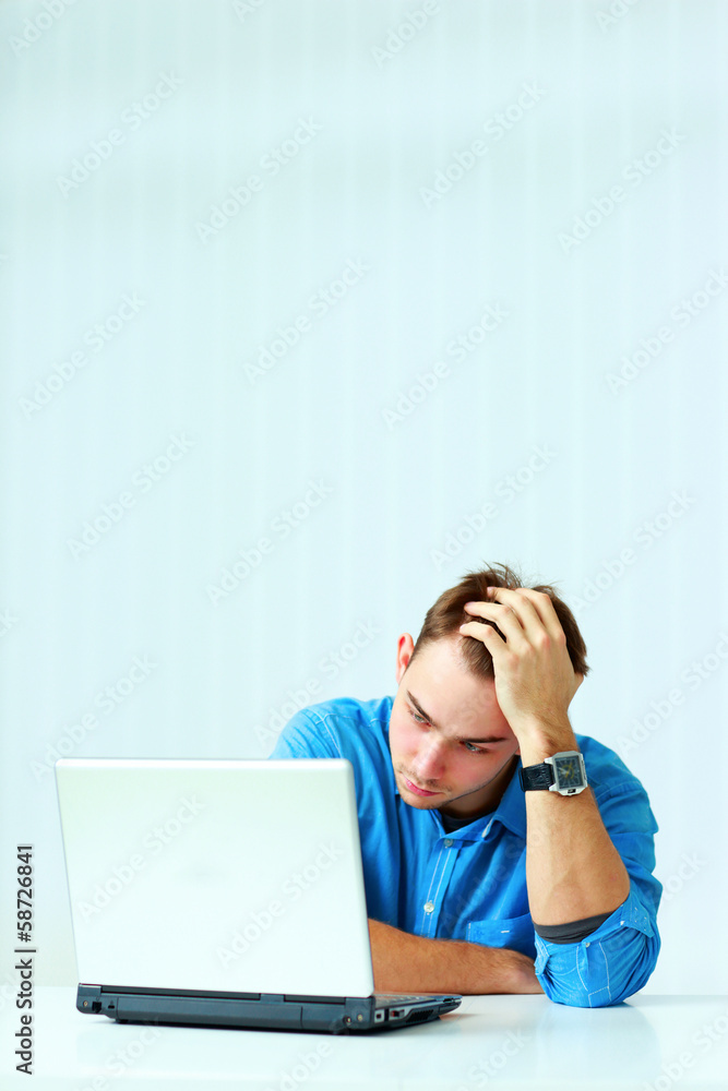 Young thoughtful businessman in blue shirt sitting Young thoughtful businessman in blue shirt sitting