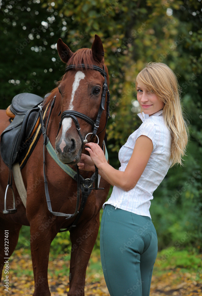 Fototapeta premium Nice blond girl with brown horse in autumn woods