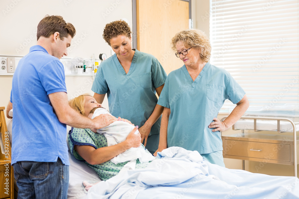 Fototapeta premium Nurses And Man Looking At Newborn Baby Sleeping On Mother