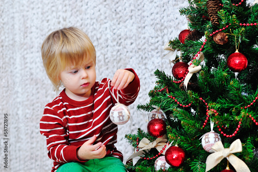 Adorable blond toddler decorating Christmas tree Adorable blond toddler decorating Christmas tree