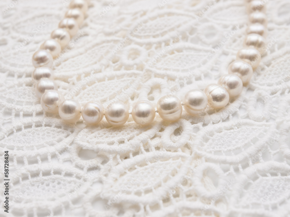 Obraz premium White pearl necklace on white lace background