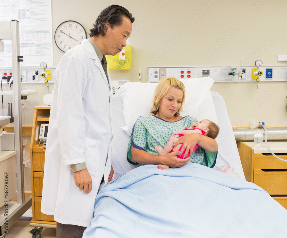 Mother And Doctor Looking At Newborn Baby Girl In Hospital Mother And Doctor Looking At Newborn Baby Girl In Hospital