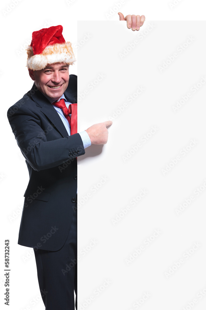 business man wearing a santa hat is pointing to a blank board business man wearing a santa hat is pointing to a blank board