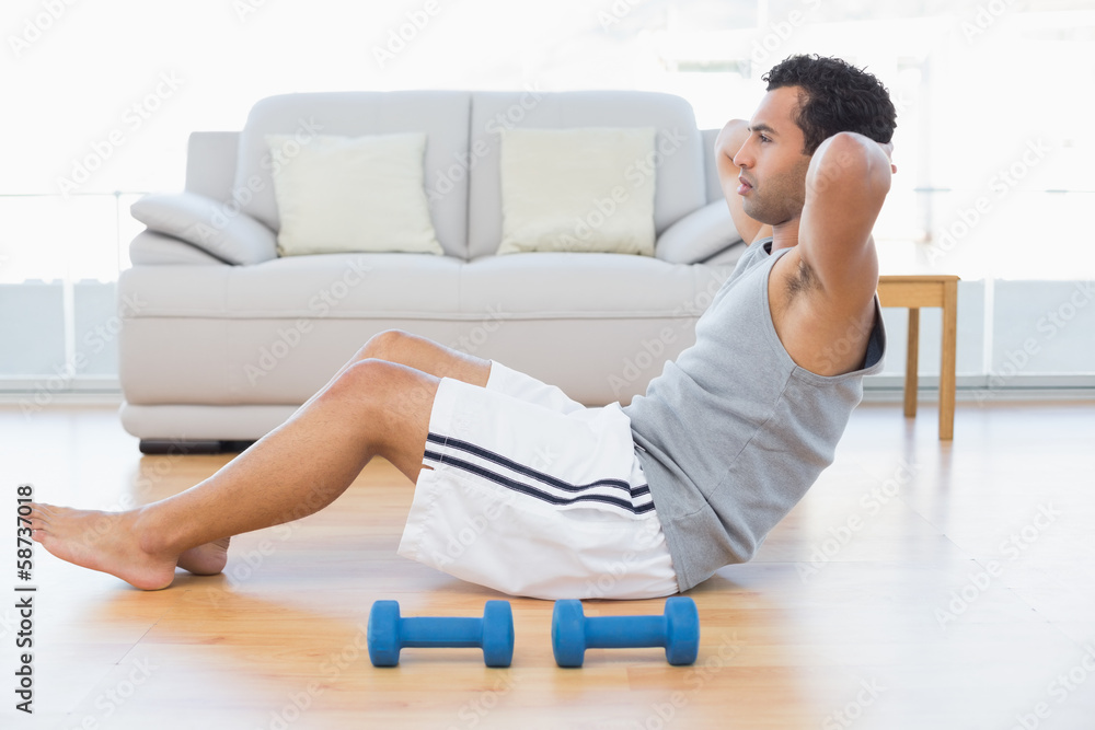 Young man doing abdominal crunches in the living room Young man doing abdominal crunches in the living room
