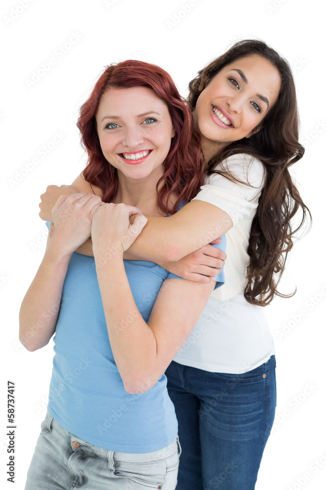 Young female embracing her friend from behind Young female embracing her friend from behind