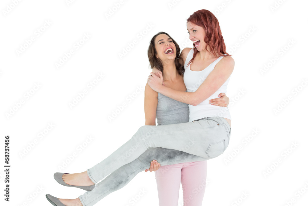 Cheerful young female carrying her happy friend Cheerful young female carrying her happy friend
