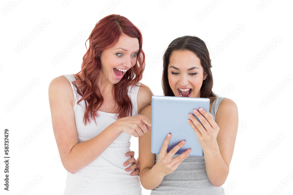 Shocked young female friends looking at digital tablet Shocked young female friends looking at digital tablet