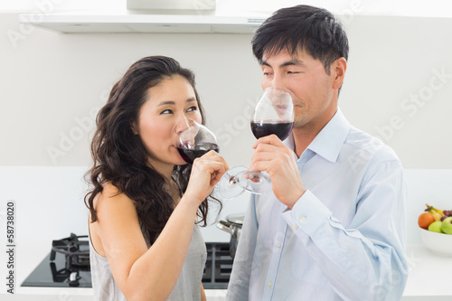 Loving young couple drinking red wine in kitchen