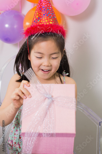 Little girl opening gift box at her birthday party