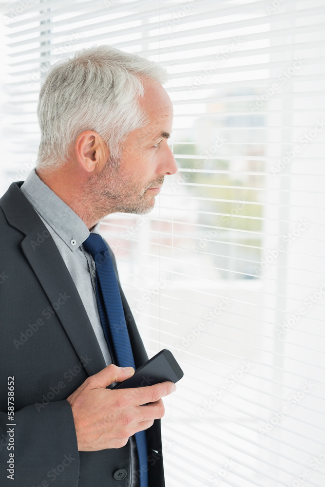 Fototapeta premium Serious mature businessman peeking in the office