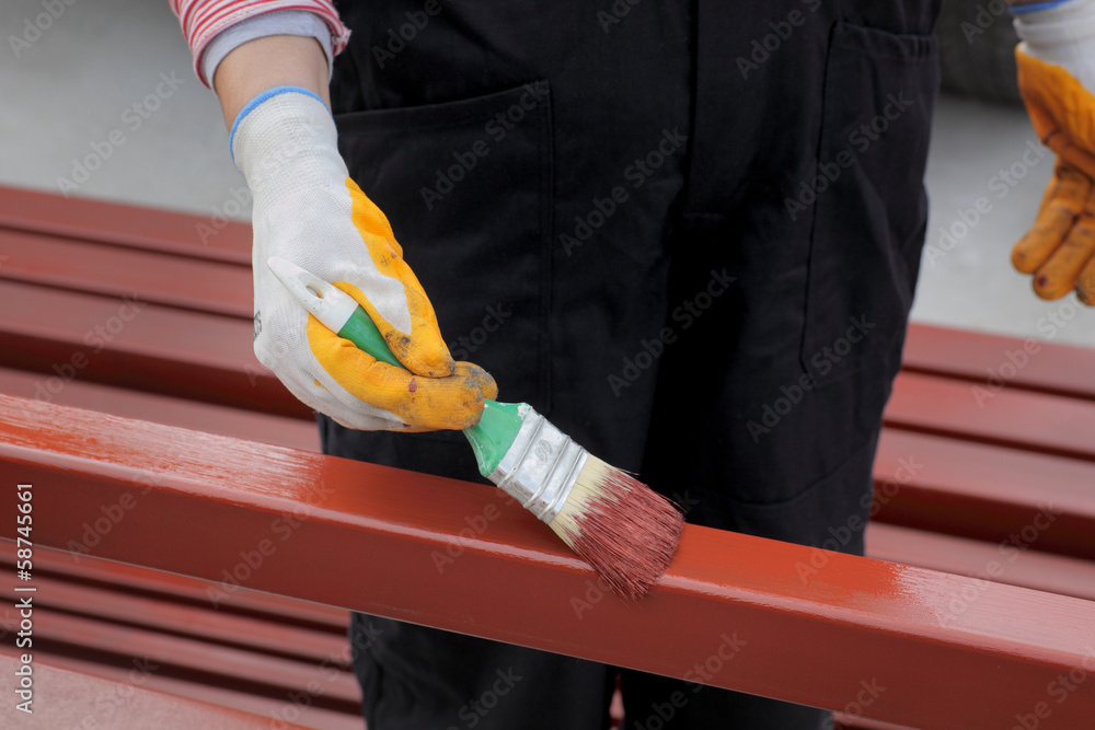 Worker painting  steel tube with paint brush focus on hand