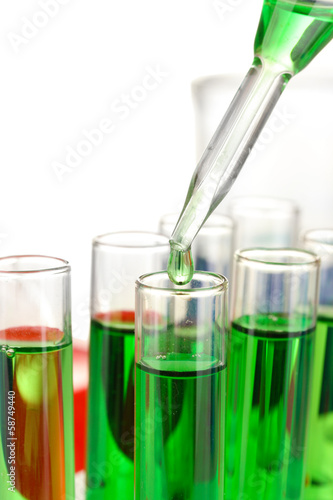 Laboratory pipette with drop of color liquid over glass test