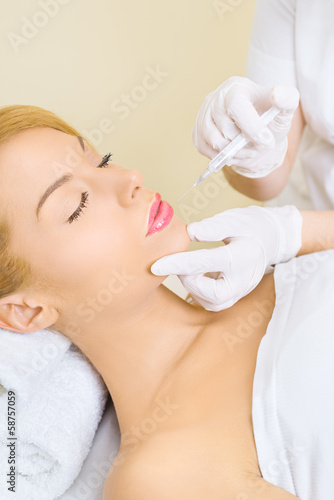 Young woman receiving botox injection in lips