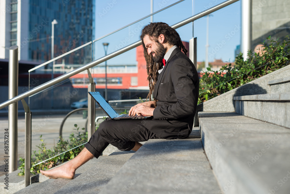Stylish elegant dreadlocks businessman using notebook Stylish elegant dreadlocks businessman using notebook