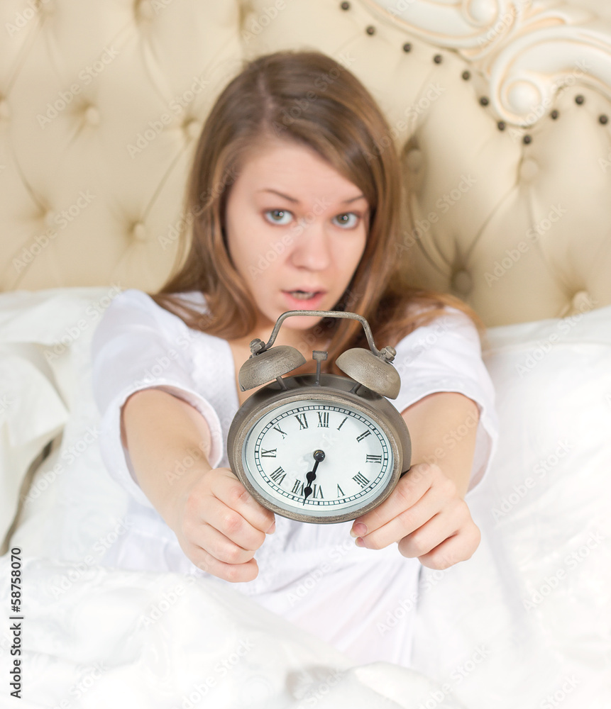 Young woman with alarmclock on the bed Young woman with alarmclock on the bed