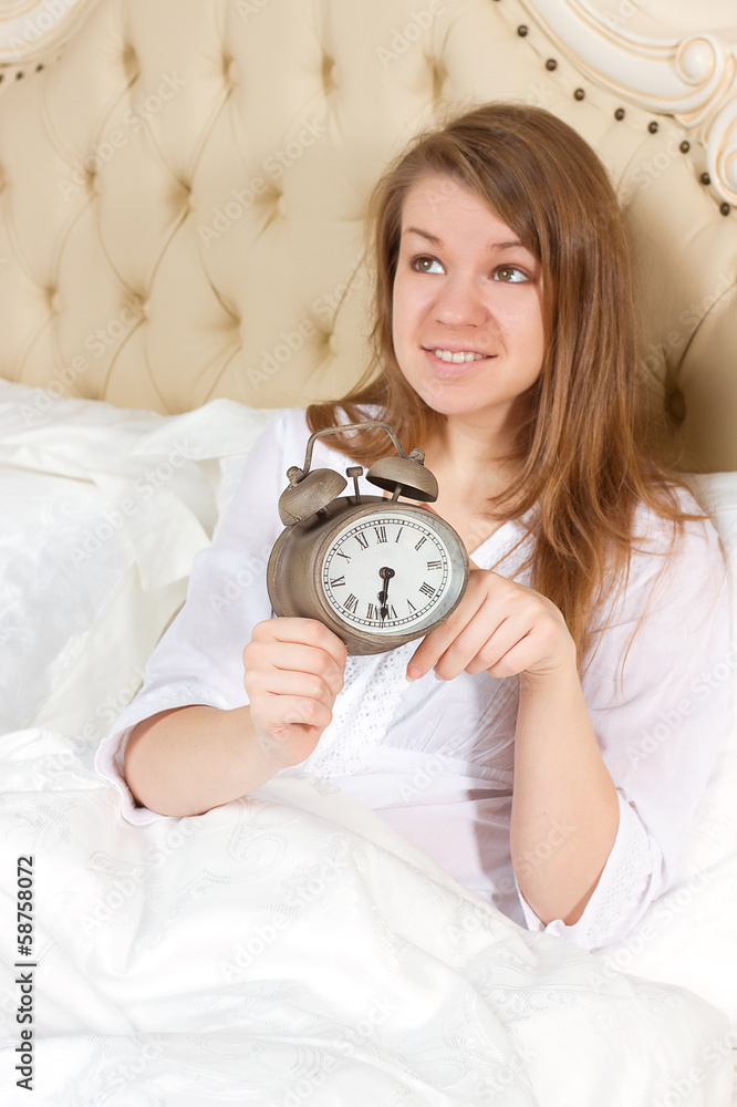 Young woman with alarmclock on the bed Young woman with alarmclock on the bed