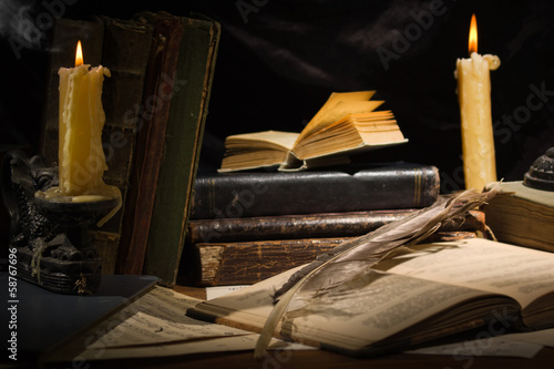 Old books and candles on wooden table