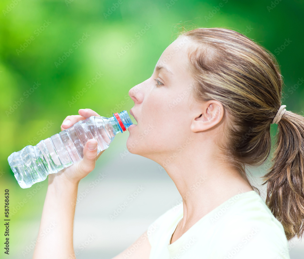 Woman drinking cold mineral water from a bottle after fitness ex Woman drinking cold mineral water from a bottle after fitness ex