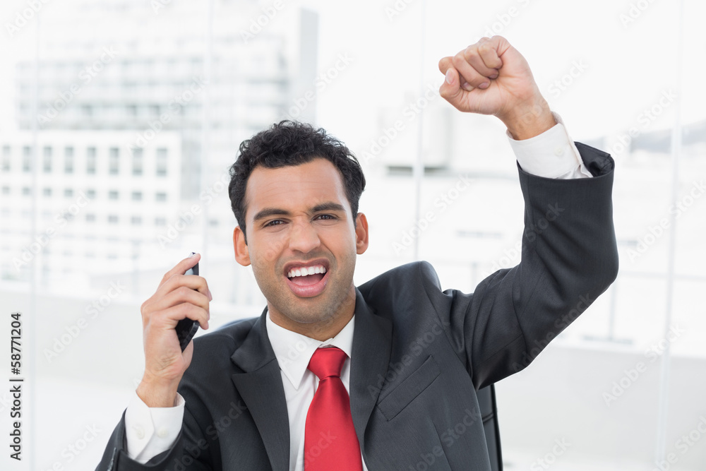 Businessman cheering with clenched fist at office Businessman cheering with clenched fist at office