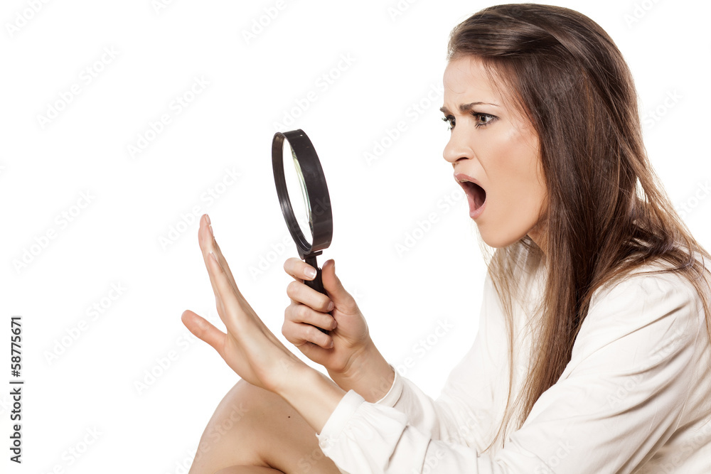 shocked young woman looking through a magnifying glass her nails shocked young woman looking through a magnifying glass her nails