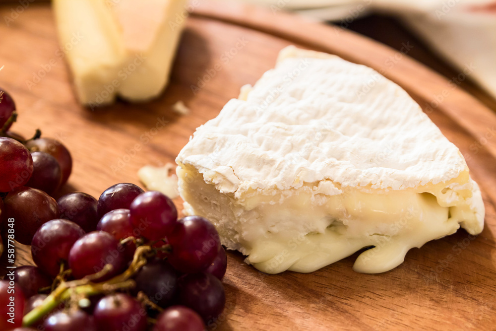 cheese on wooden plate with grapes