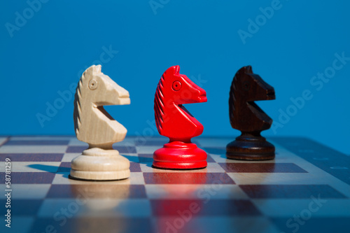 Three chess knight on chessboard on blue background